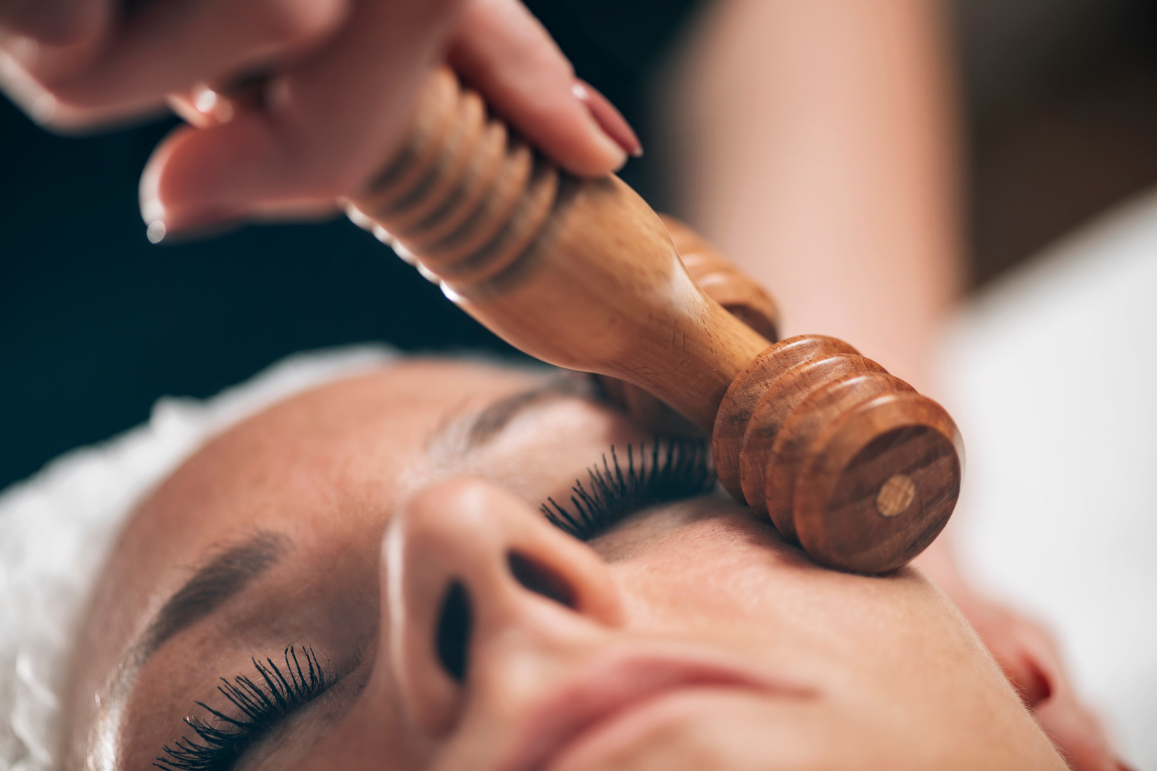 Maderotherapy Face Massage. Massaging Woman's Face with Wooden Double Roller Massager